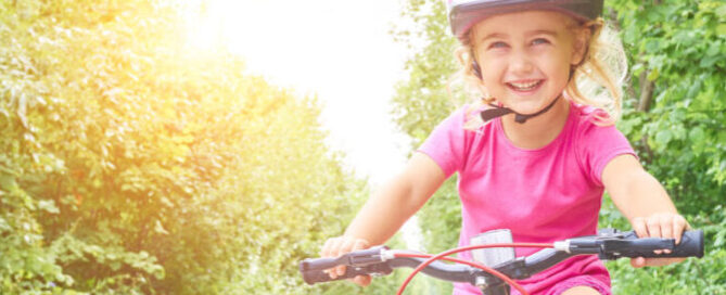 Happy Child Riding A Bike In Outdoor.