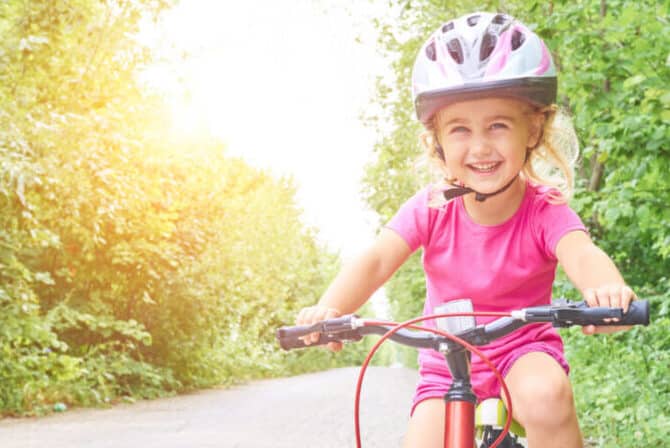 Happy Child Riding A Bike In Outdoor.