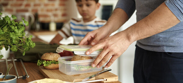 Close Up Of Father Making Lunch Box For Son