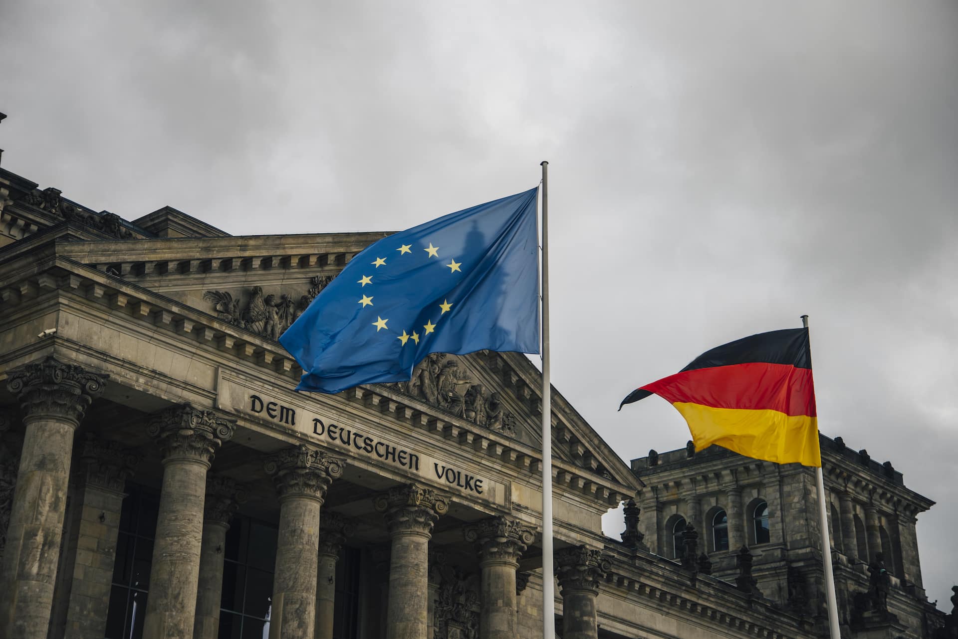 Abbildung des Reichstagsgebäudes in Berlin, Deutschland, mit der Deutschland-Flagge und einer Flagge der Europäischen Union.