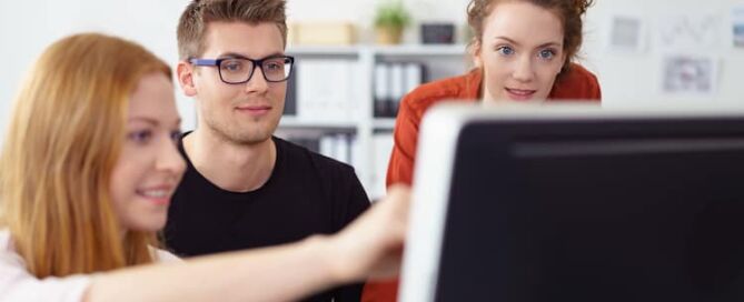 Junges motiviertes Business-Team aus zwei Frauen und einem jungen Mann, die zusammen an einem Desktop-Computer arbeiten. Symbolbild für unsere "Kunststoffverbesserer" und deren Auswirkung auf Kunststoff-Innovation und die Transformation der Kunststoff Kreislaufwirtschaft.
