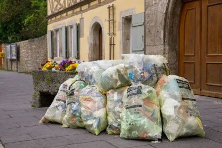 Stapel gelblicher Wertstoffsack-Müllsäcke, die mit recycelbarem Plastik- und Pappmüll gefüllt sind, warten auf die Abholung.
